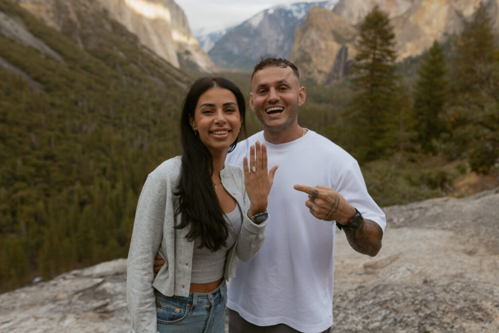 Newly engaged couple posing at Tunnel View overlook in Yosemite