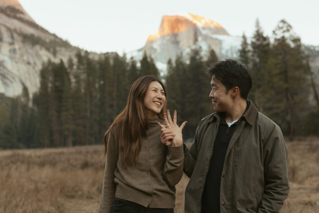 Emotional surprise proposal in Cooks Meadow Yosemite as Johnny kneels and Lydia reacts with laughter and tears.
