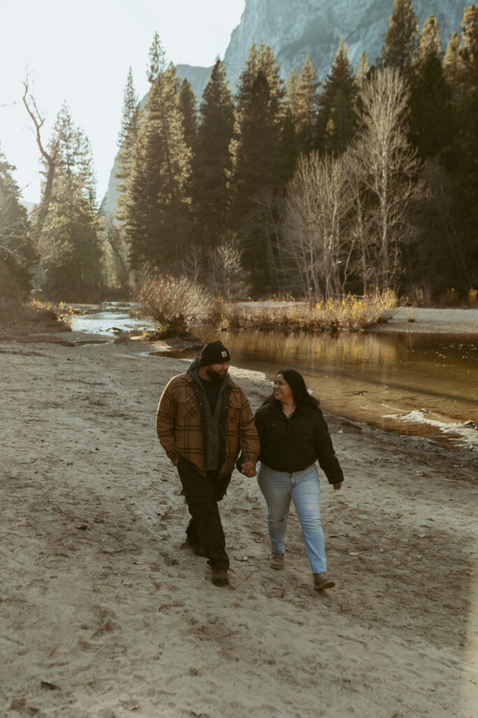 A couple walks along the river in Cooks Meadow Yosemite national Park 