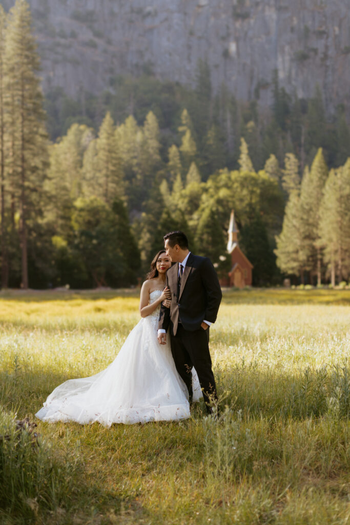 Bride and Groom take photos in cooks meadow with Yosemite chapel in the background